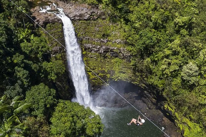 Zipline rider soaring over a 250-foot waterfall on the Hamakua Coast near Akaka Falls Hilo Hawaii